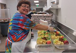 This image of a cafeteria worker preparing lunches will link to the Child Nutrition department page.